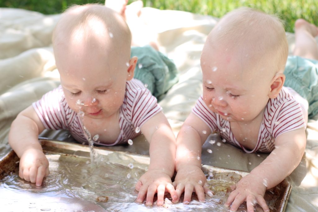 Twins splashing water in a cookie sheet