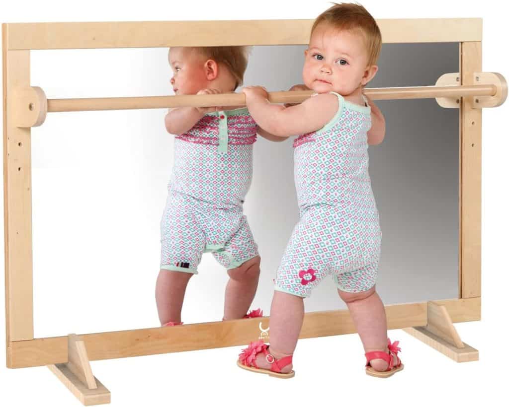 baby pulling-up to stand at a Montessori mirror and pull up bar. 