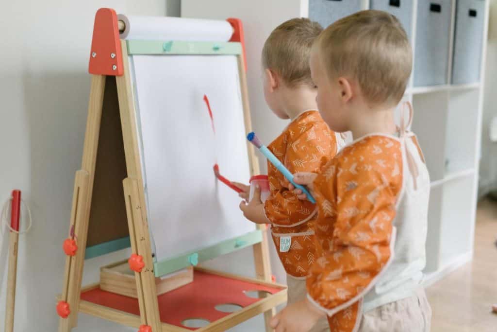 toddlers painting on an art easel.
