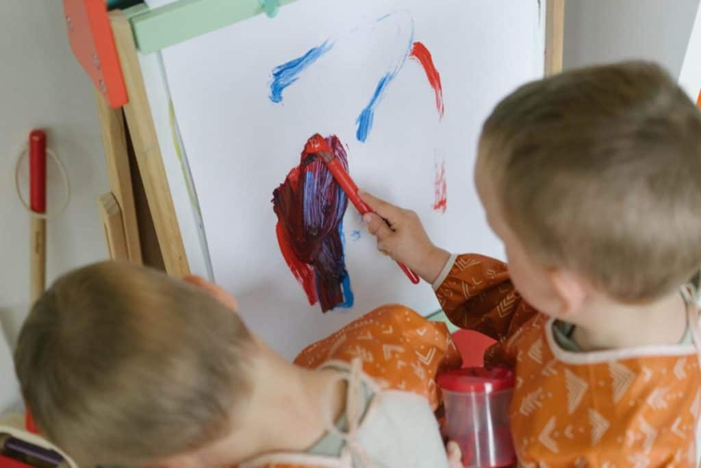 toddlers painting on an art easel.