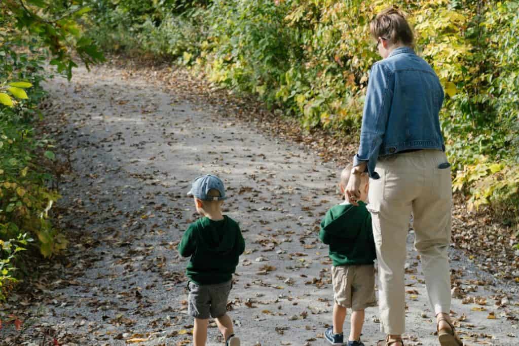 Mom and twins walking on a path in the fall.