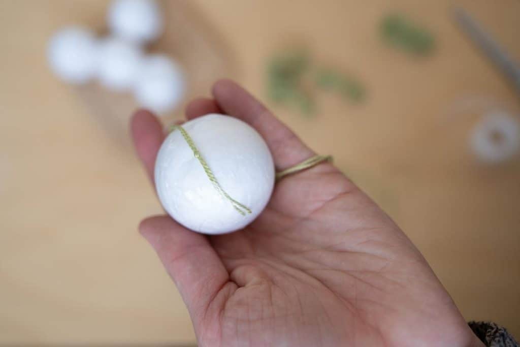 Styrophome ball with a piece of embroidery thread taped to it.