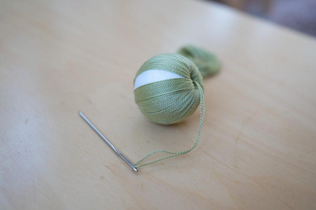 Ball wrapped in embroidery thread with a needle.