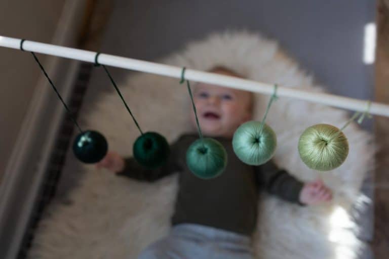 Baby lying under a baby mobile.