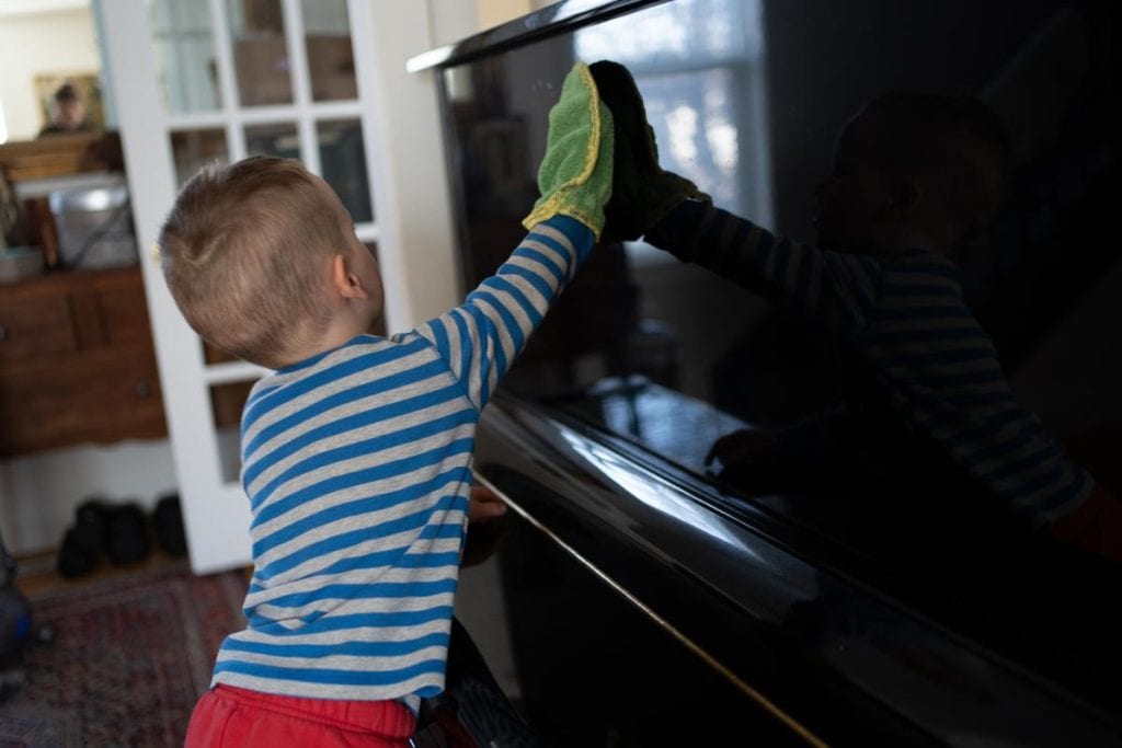 Child dusting with a dusting mitt.