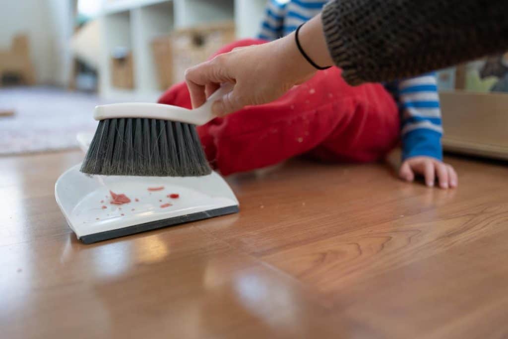 Child sweeping with a dustpan and broom.
