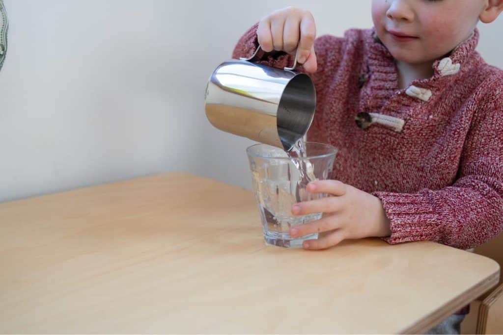 Child pouring water from a pitcher.