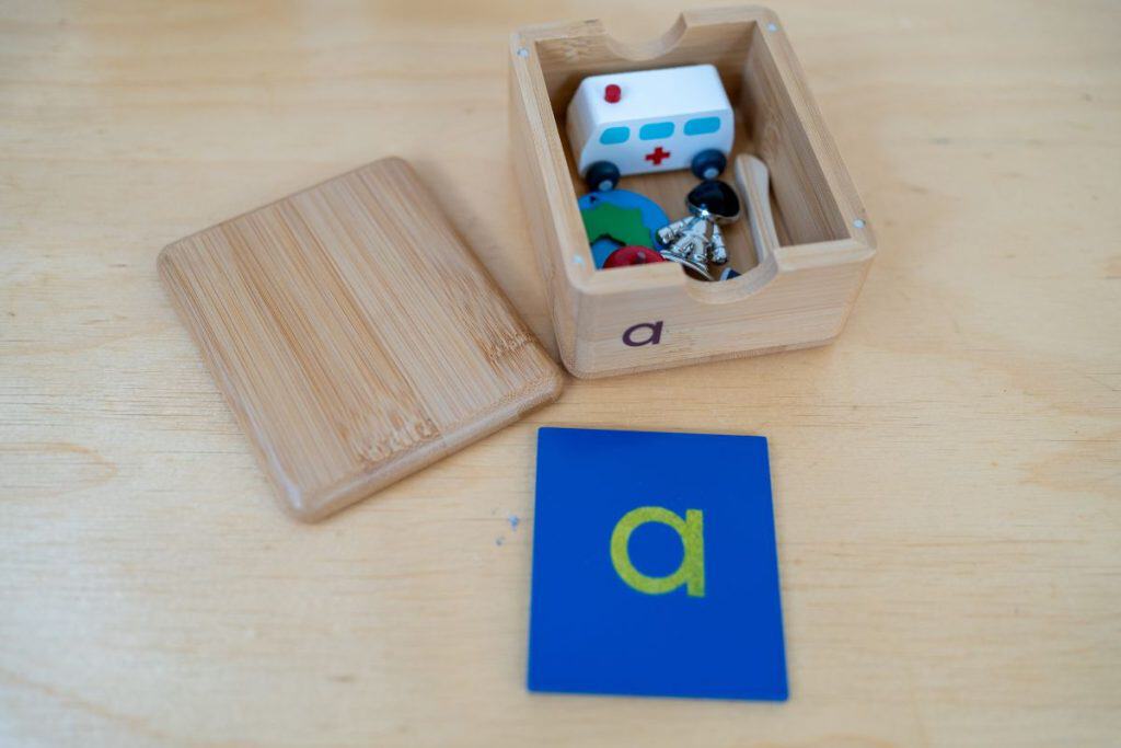 Small box with objects starting with 'a', small sandpaper letter 'a'.