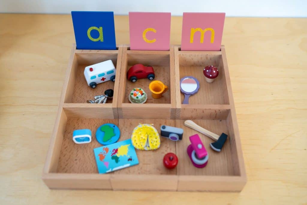 objects sorted in a tray for the sounds 'a', 'c' and 'm'.